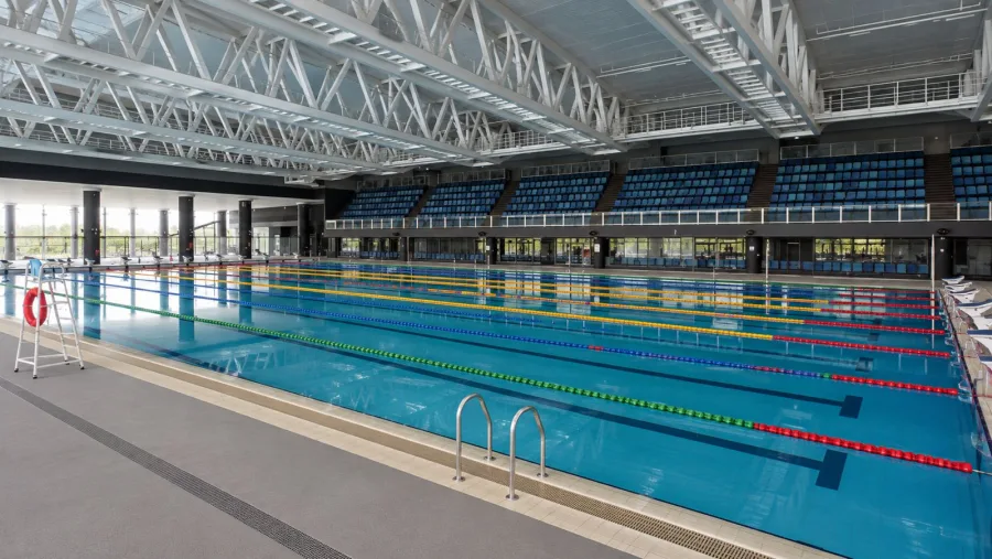 AI-generated impression of an indoor competition swimming pool with tiered grandstand seating at Punggol Swimming Complex